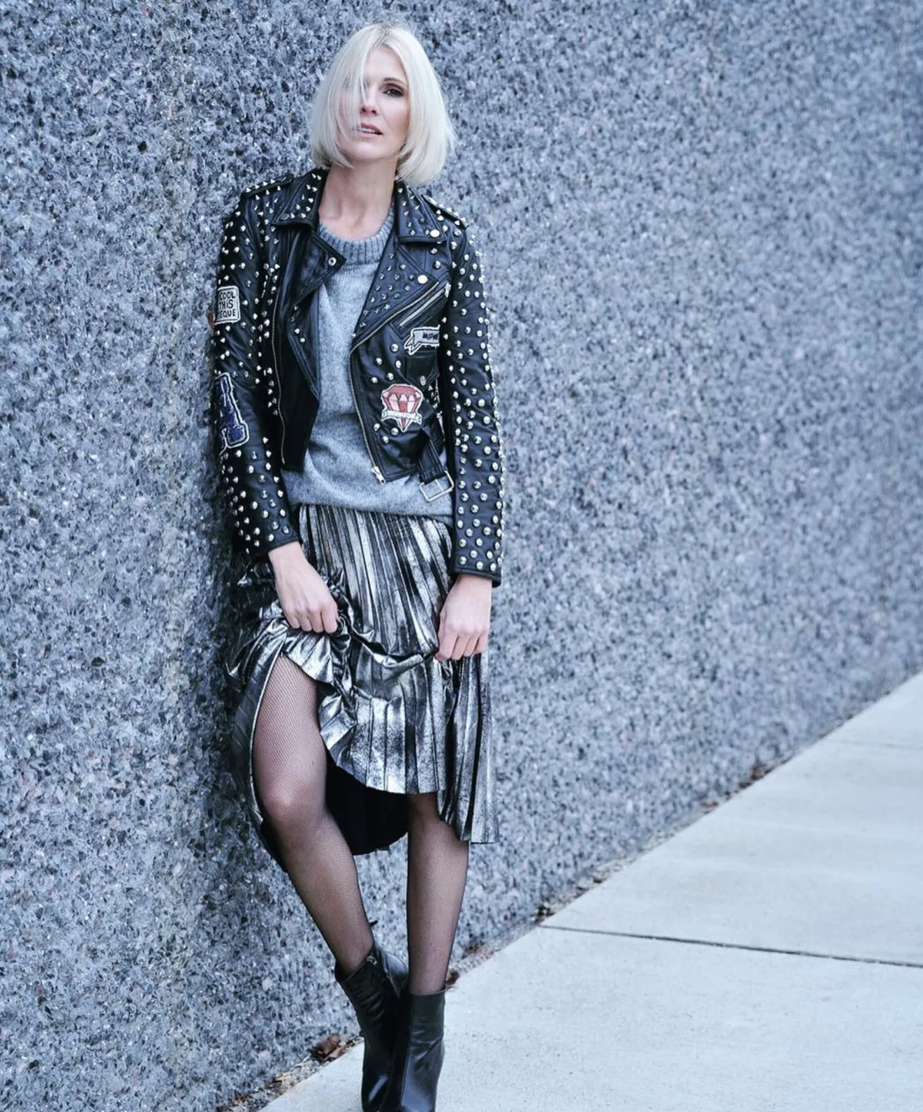 Frau mit Nietenlederjacke und Metallicrock an einer Waschbetonwand