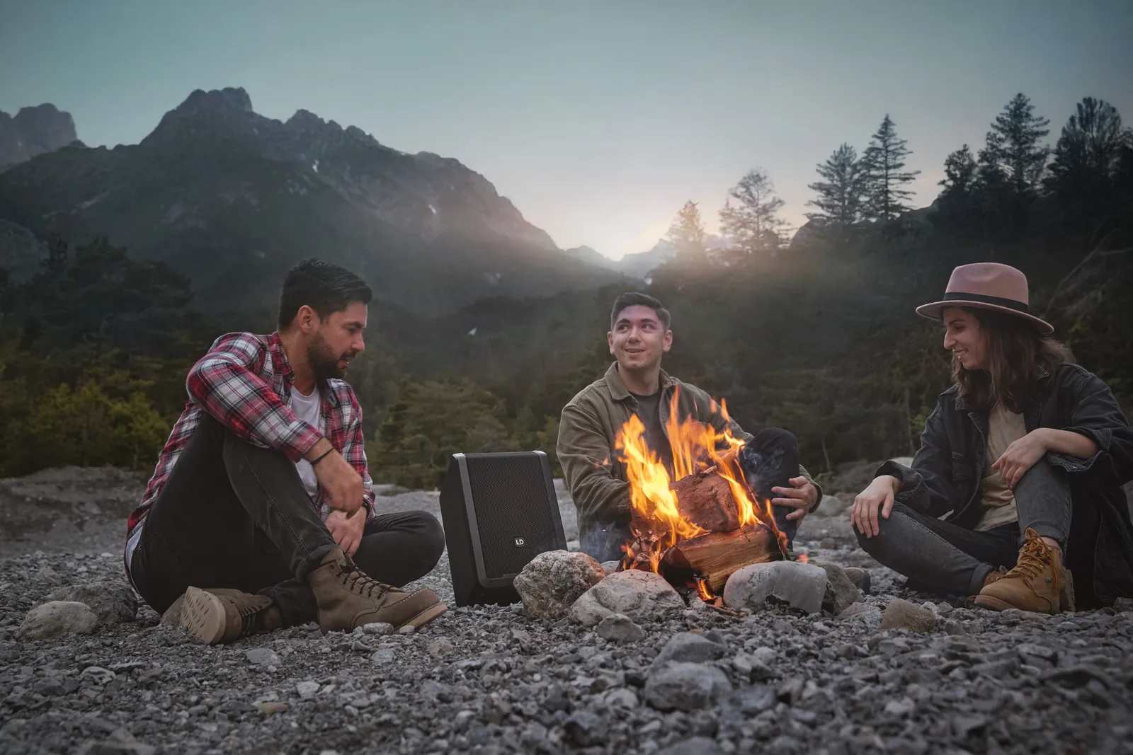 Freunde am Lagerfeuer in den Bergen mit Lautsprecher, Kampagne
