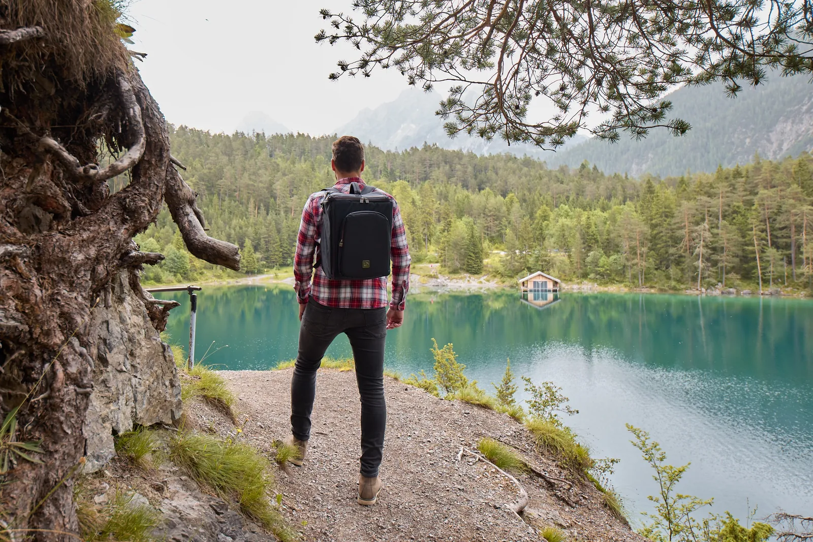 Person mit Rucksack über einem türkisen Bergsee, Kampagne