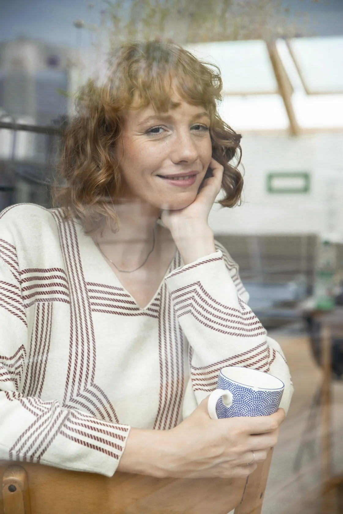 Laura hinter einer Glasscheibe mit Spiegelung