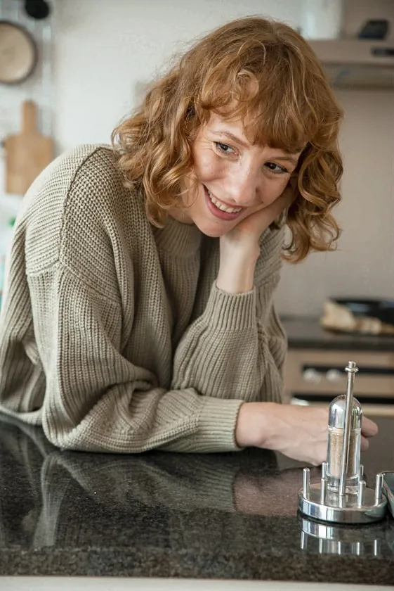Laura im grünen Strickpullover an der Küchentheke